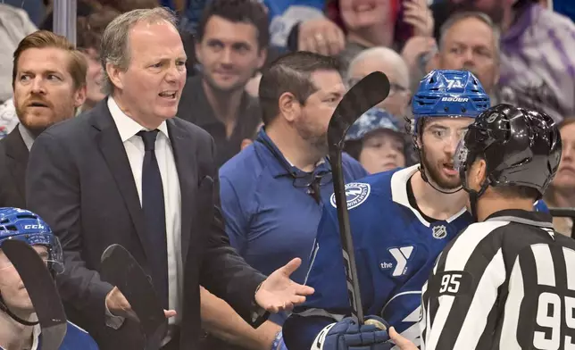 Tampa Bay Lightning head coach Jon Cooper talks with linesman Jonny Murray (95) during the third period of an NHL hockey game against the Nashville Predators, Sunday, March 29, 2026, in Tampa, Fla. (AP Photo/Jason Behnken)