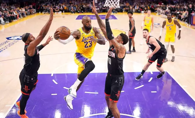 Los Angeles Lakers forward LeBron James, second from left, passes the ball as Houston Rockets guard Josh Okogie, left, and forward Jabari Smith Jr. defend during the first half in Game 1 of a first-round NBA playoffs basketball series Saturday, April 18, 2026, in Los Angeles. (AP Photo/Mark J. Terrill)