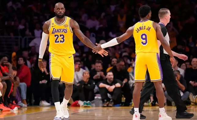 Los Angeles Lakers forward LeBron James, left, slaps hands with guard Bronny James during the first half in Game 1 of a first-round NBA playoffs basketball series against the Houston Rockets, Saturday, April 18, 2026, in Los Angeles. (AP Photo/Mark J. Terrill)