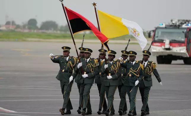 Soldiers march carrying the Vatican flag, right, and Angolan flag prior to Pope Leo XIV's departure for Equatorial Guinea, at the airport in Luanda, Angola, Tuesday, April 21, 2026. (AP Photo/Themba Hadebe)