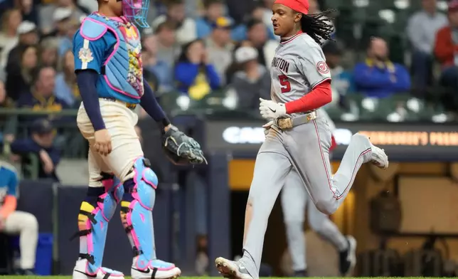 Washington Nationals' CJ Abrams (5) scores on an RBI single hit by Luis García Jr. as Milwaukee Brewers catcher William Contreras, left, looks on during the ninth inning of a baseball game, Friday, April 10, 2026, in Milwaukee. (AP Photo/Kayla Wolf)