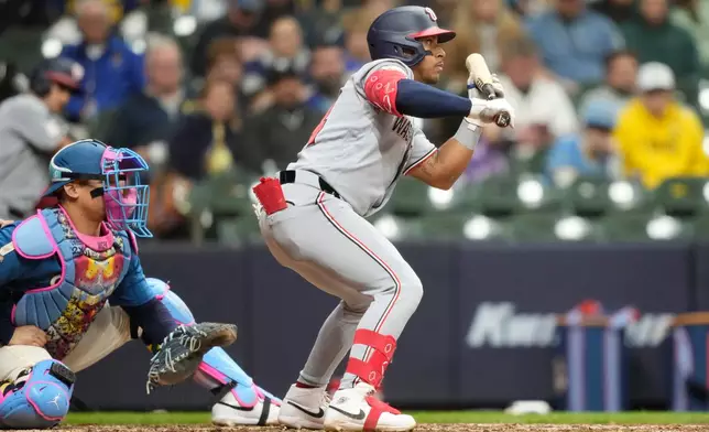 Washington Nationals' Jorbit Vivas hits a sacrifice bunt as Milwaukee Brewers catcher William Contreras, left, looks on during the ninth inning of a baseball game, Friday, April 10, 2026, in Milwaukee. (AP Photo/Kayla Wolf)