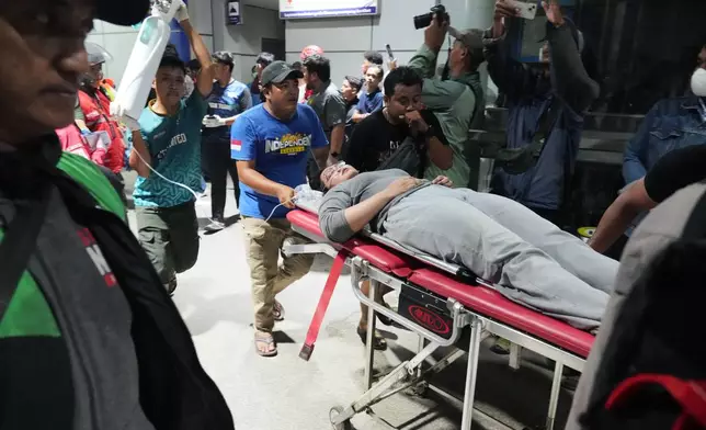 People push a woman on a stretcher following a train collision in Bekasi, Indonesia, Monday, April 27, 2026. (AP Photo/Achmad Ibrahim)