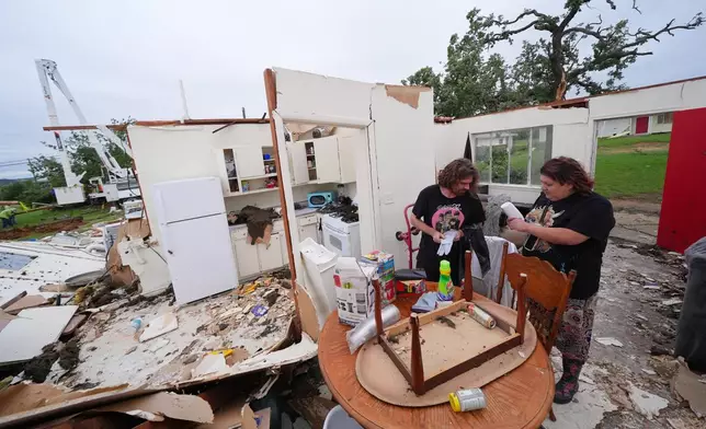 Christopher Hester, left center, talks to friend Brianna Corter, as he salvages belongings from his storm-damaged home in Mineral Wells, Texas, Wednesday, April 29, 2026. (AP Photo/Julio Cortez)