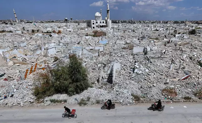 Motorcyclists pass destruction in the al-Qadam area on the outskirts of Damascus, Syria, Wednesday, April 29, 2026 in a area that was heavily bombed by forces loyal to former Syrian President Bashar Assad during the Syrian war. (AP Photo/Omar Sanadiki)