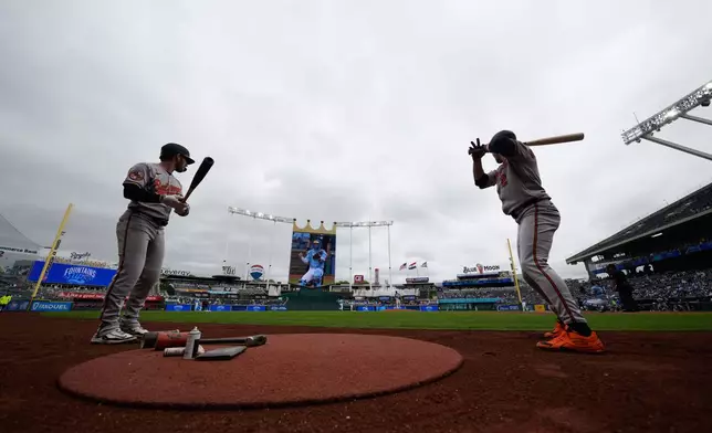 Baltimore Orioles' Taylor Ward, left, and Gunnar Henderson (2) warm up on deck before a baseball game against the Kansas City Royals, Wednesday, April 22, 2026, in Kansas City, Mo. (AP Photo/Charlie Riedel)