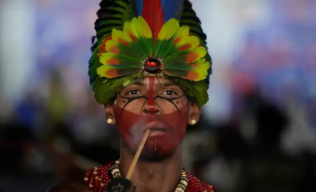 A Pataxo man smokes a traditional pipe before a march at the Acampamento Terra Livre 2026, an Indigenous mobilization focused on land rights and environmental protection, in Brasilia, Brazil, Thursday, April 9, 2026. (AP Photo/Eraldo Peres)
