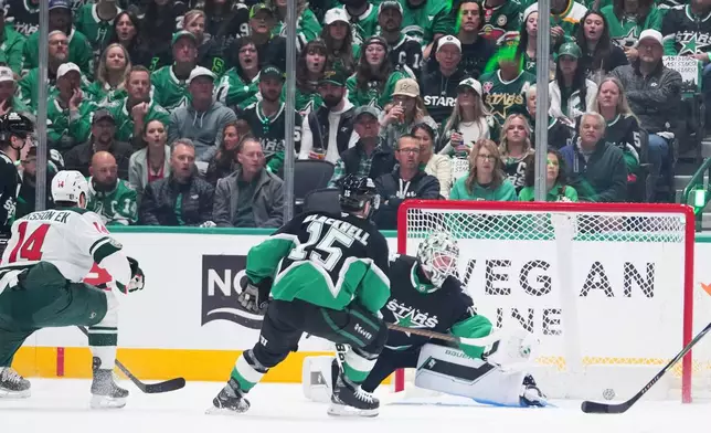 A shot by Minnesota Wild center Joel Eriksson Ek (14) enters the net of Dallas Stars goaltender Jake Oettinger, center, for a goal during the first period in Game 1 of a first-round NHL Stanley Cup playoffs hockey series, Saturday, April 18, 2026, in Dallas, Texas. (AP Photo/Julio Cortez)