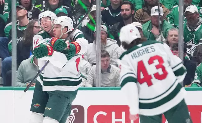 Minnesota Wild left wing Matt Boldy, left, congratulates Joel Eriksson Ek, center, after his power play goal against the Dallas Stars during the first period in Game 1 of a first-round NHL Stanley Cup playoffs hockey series, Saturday, April 18, 2026, in Dallas, Texas. (AP Photo/Julio Cortez)