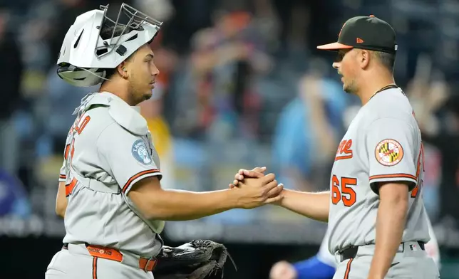 Baltimore Orioles catcher Samuel Basallo, left, and relief pitcher Cameron Foster celebrate after their baseball game against the Kansas City Royals, Monday, April 20, 2026, in Kansas City, Mo. (AP Photo/Charlie Riedel)