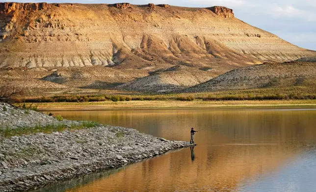 FILE - Nick Gann fishes in Firehole Canyon, Friday, Aug. 5, 2022, on the far northeastern shore of Flaming Gorge Reservoir, in Wyoming. (AP Photo/Rick Bowmer, File)