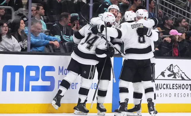 Los Angeles Kings right wing Alex Laferriere (14) celebrates an empty net goal against the Seattle Kraken with defenseman Joel Edmundson, second from left, defenseman Drew Doughty (8) and center Scott Laughton, right, during the third period of an NHL hockey game Monday, April 13, 2026, in Seattle. (AP Photo/Lindsey Wasson)