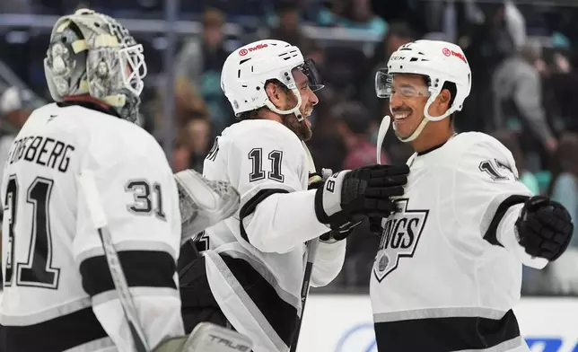 Los Angeles Kings goaltender Anton Forsberg (31), center Anze Kopitar (11) and right wing Mathieu Joseph (17) celebrate a win over the Seattle Kraken in an NHL hockey game Monday, April 13, 2026, in Seattle. (AP Photo/Lindsey Wasson)