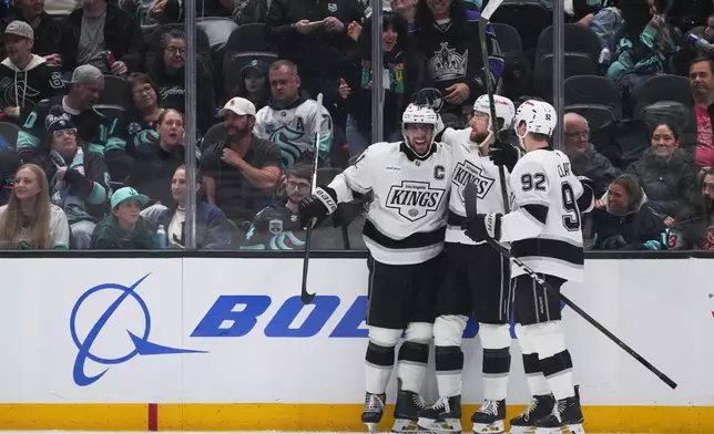 Los Angeles Kings right wing Adrian Kempe, center, celebrates his goal with center Anze Kopitar, left, and defenseman Brandt Clarke, right, against the Seattle Kraken during the third period of an NHL hockey game Monday, April 13, 2026, in Seattle. (AP Photo/Lindsey Wasson)