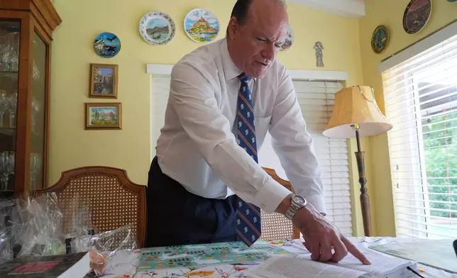 Nick Gutiérrez, President of the National Association of Cuban Landowners in Exile, shows a book published by the Cuban government of private properties they seized, Tuesday, April 21, 2026, in Coral Gables, Fla. (AP Photo/Marta Lavandier)