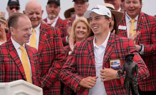 Matt Fitzpatrick, of England, right, puts on the tartan plaid jacket after winning the RBC Heritage golf tournament Sunday, April 19, 2026, in Hilton Head, S.C. (AP Photo/Mike Stewart)