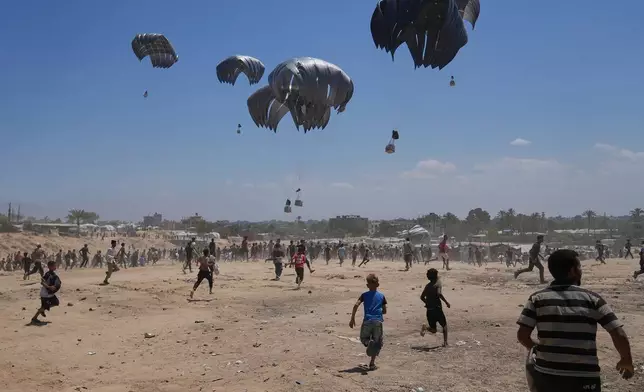 FILE - Palestinians rush to collect humanitarian aid airdropped by parachutes into Zawaida in the central Gaza Strip, Monday, Aug. 4, 2025. (AP Photo/Abdel Kareem Hana, File)