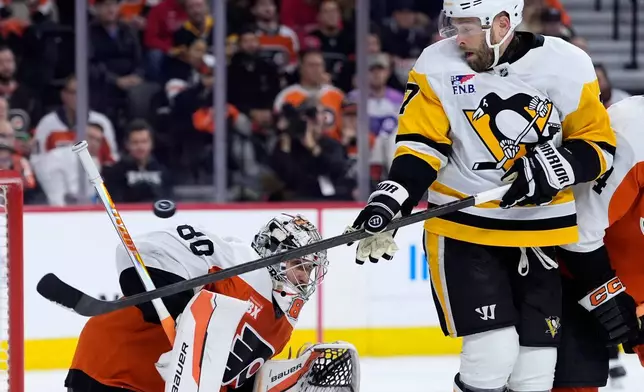 Pittsburgh Penguins' Bryan Rust, right, attempts to get the puck past Philadelphia Flyers' Dan Vladar during the first period of Game 6 in the first round of the NHL hockey Stanley Cup playoffs series Wednesday, April 29, 2026, in Philadelphia. (AP Photo/Matt Slocum)