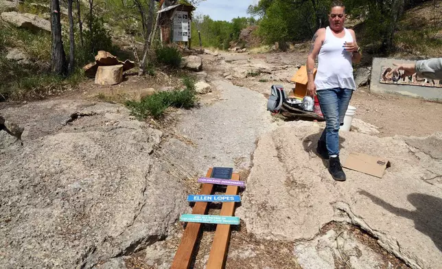 Crystina Page, whose son's body was among nearly 200 found decomposing in a southern Colorado funeral home in 2023, looks at a set of memorial signs for the victims in Colorado Springs, Colo., on Wednesday, April 22, 2026. (AP Photo/Thomas Peipert)