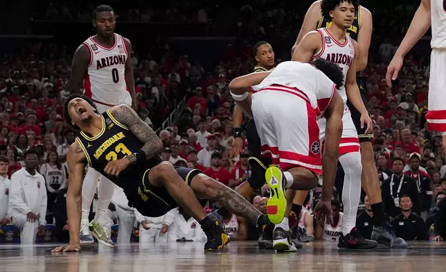 Michigan forward Yaxel Lendeborg (23) falls after play against Arizona during the first half of an NCAA college basketball tournament semifinal game at the Final Four, Saturday, April 4, 2026, in Indianapolis. (AP Photo/Abbie Parr)