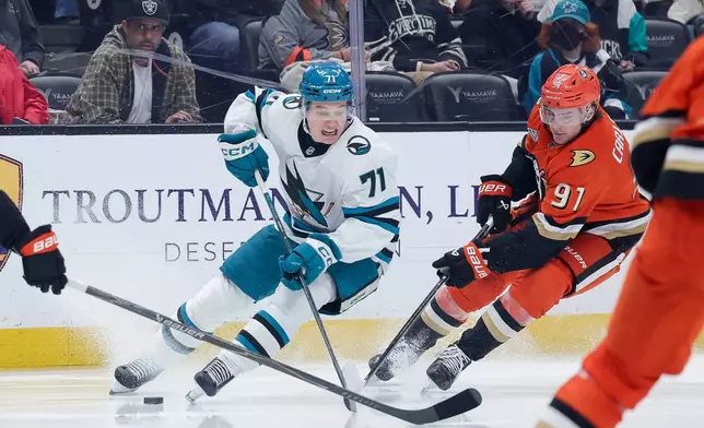 San Jose Sharks center Macklin Celebrini, left, moves the puck against Anaheim Ducks center Leo Carlsson during the second period of an NHL hockey game Thursday, April 9, 2026 in Anaheim, Calif. (AP Photo/Ryan Sun)