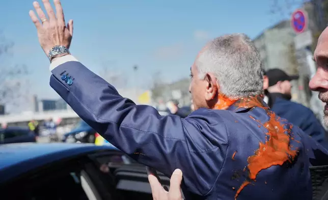 Iran's Reza Pahlavi, exiled son of Shah Reza Pahlavi, waves to supporters after he was attacked with a red fluid following a news conference in Berlin, Germany, Thursday, April 23, 2026. (AP Photo/Markus Schreiber)