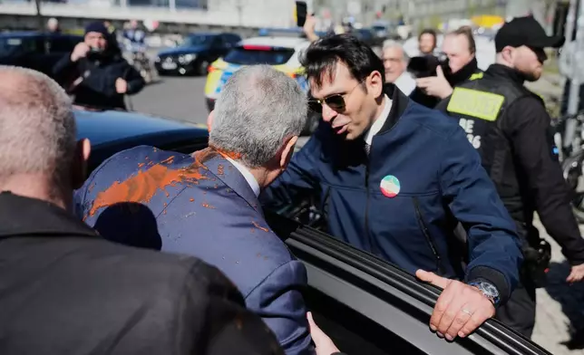 Iran's Reza Pahlavi, exiled son of Shah Reza Pahlavi, is protected by security after he was attacked with a red fluid, following a news conference in Berlin, Germany, Thursday, April 23, 2026. (AP Photo/Markus Schreiber)