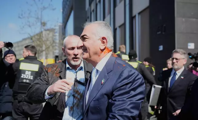 Iran's Reza Pahlavi, exiled son of Shah Reza Pahlavi, is protected by security after he was attacked with a red fluid, following a news conference in Berlin, Germany, Thursday, April 23, 2026. (AP Photo/Markus Schreiber)