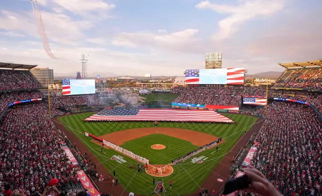 Three North American AT-6 Texan aircraft fly over during the national anthem prior to an opening-day baseball game between the Los Angeles Angels and the Seattle Mariners, Friday, April 3, 2026, in Anaheim, Calif. (AP Photo/Mark J. Terrill)