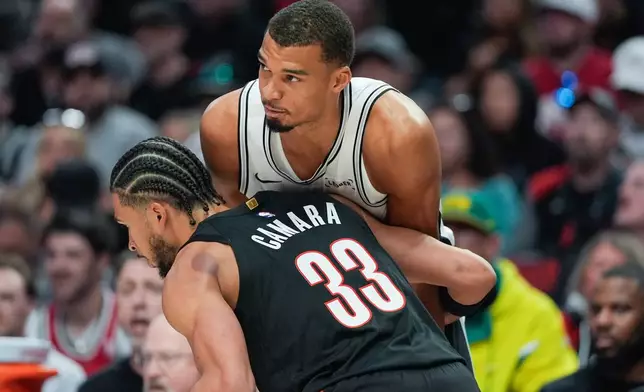 San Antonio Spurs forward/center Victor Wembanyama is guarded by Portland Trail Blazers forward Toumani Camara during the first half in Game 4 of a first-round NBA basketball playoffs series in Portland, Ore., Sunday, April 26, 2026. (AP Photo/Jenny Kane)