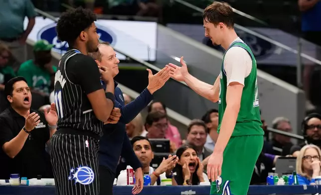 Dallas Mavericks forward Cooper Flagg, right, is greeted at the bench by assistant coach Frank Vogel, center left, as Orlando Magic's Jase Richardson, left, stands by in the second half of an NBA basketball game Friday, April 3, 2026, in Dallas. (AP Photo/Tony Gutierrez)