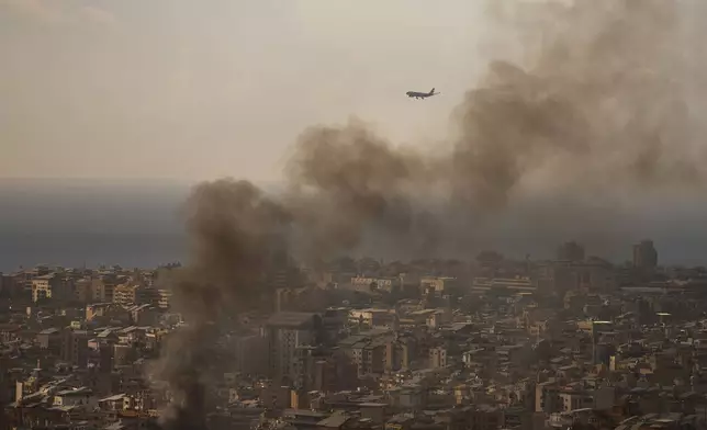 A commercial plane is preparing to land at Beirut Airport as smoke rises from Israeli airstrikes in Dahiyeh, a southern suburb of Beirut, Lebanon, Sunday, April 5, 2026. (AP Photo/Emilio Morenatti)