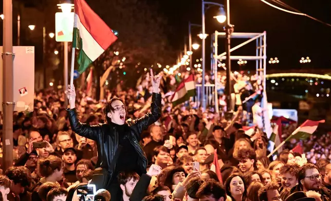 A man waves a Hungarian flag as he celebrates in the streets after the announcement of partial results of the Hungarian parliamentary election in Budapest, Hungary, Sunday, April 12, 2026. (AP Photo/Denes Erdos)
