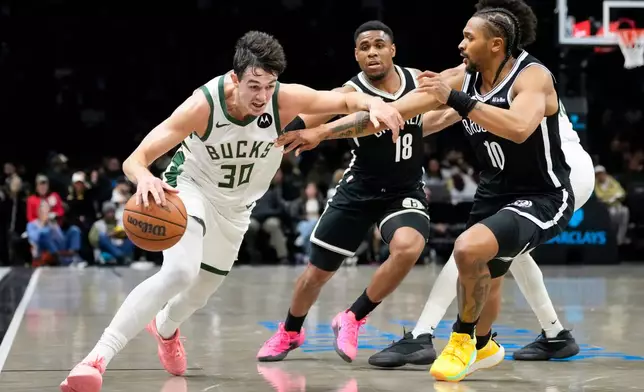 Milwaukee Bucks guard Cormac Ryan (30) drives past Brooklyn Nets guard Tyson Etienne (10) and Brooklyn Nets guard Malachi Smith (18) during the first half of an NBA basketball game, Tuesday, April 7, 2026, in New York. (AP Photo/Yuki Iwamura)