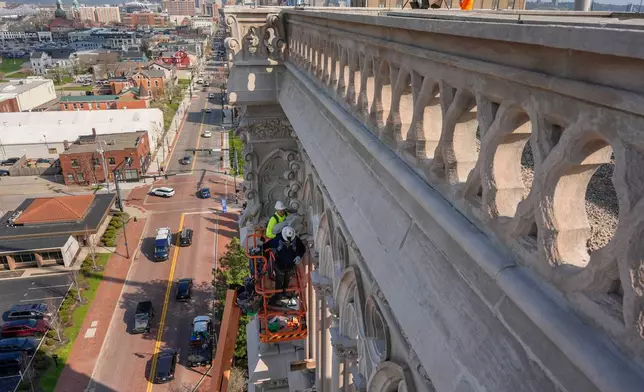 The final new terra cotta gargoyle is installed by Cole Burklund, in the bright yellow, and Blake Priest using a cherry picker high on the Cathedral Basilica of the Assumption, known as "America's Notre Dame," in Covington, Ky., on Monday, March 30, 2026. (AP Photo/Carolyn Kaster)