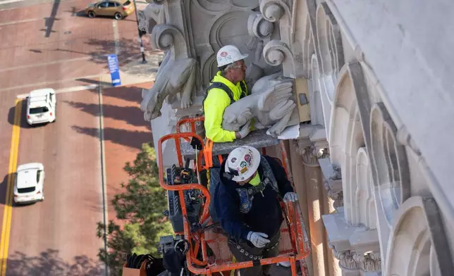 The final new terra cotta gargoyle is installed by Cole Burklund, top, and Blake Priest using a cherry picker high on the Cathedral Basilica of the Assumption, known as "America's Notre Dame," in Covington, Ky., on Monday, March 30, 2026. (AP Photo/Carolyn Kaster)