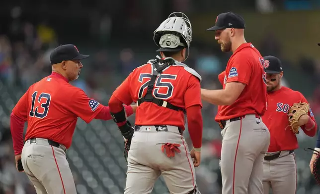 Boston Red Sox starter Garrett Crochet, front right, hands the ball to manager Alex Cora (13) for a pitching change during the second inning of a baseball game against the Minnesota Twins, Monday, April 13, 2026, in Minneapolis. (AP Photo/Abbie Parr)