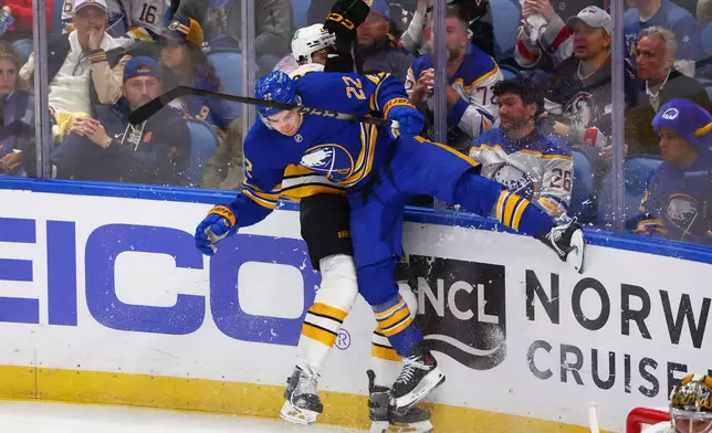 Boston Bruins defenseman Andrew Peeke (26) is checked by Buffalo Sabres right wing Jack Quinn (22) during the third period in Game 1 of a first-round NHL hockey Stanley Cup playoff series, Sunday, April 19, 2026, in Buffalo, N.Y. (AP Photo/Jeffrey T. Barnes)
