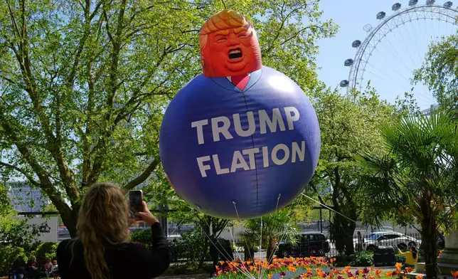 A passer-by takes a picture of a balloon in the caricature of US President Donald Trump as Britain's Liberal Democrat party launch their new "Trumpflation" campaign as latest inflation figures reveal the impact of the Iran War on prices in the UK, in London, Wednesday, April 22, 2026. (AP Photo/Kirsty Wigglesworth)