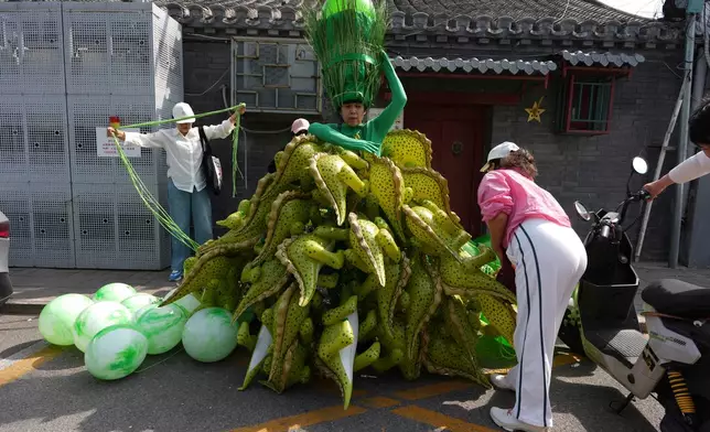 Chinese artiste Kong Ning wears a costumes assembled with dinosaur balloons to commemorate Earth Day in Beijing, Wednesday, April 22, 2026. (AP Photo/Ng Han Guan)