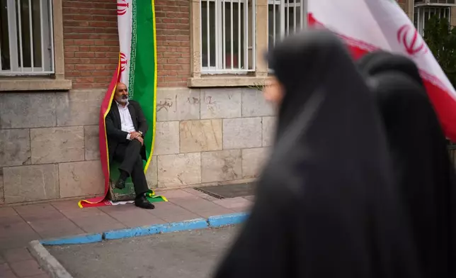 FILE - A man leans against an Iranian flag banner during a government-sponsored protest attended by medical workers against the U.S.-Israeli military campaign outside Imam Khomeini Hospital in Tehran, Iran, Monday, April 6, 2026. (AP Photo/Francisco Seco, File)