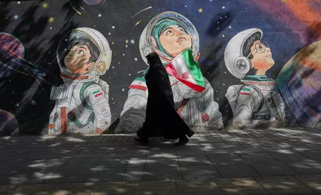 FILE - A woman walks past a mural in Tehran, Iran, Wednesday, April 8, 2026. (AP Photo/Francisco Seco, File)