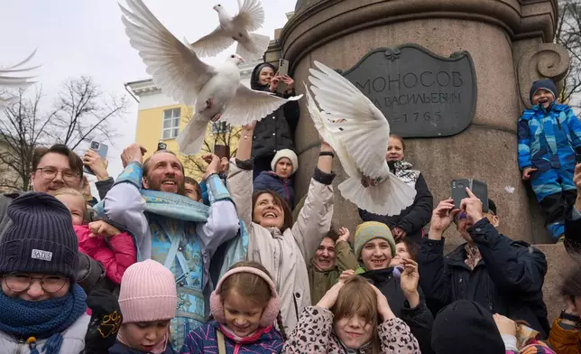 FILE - Orthodox priest Father Simeon, center left, with children and their parents, releases birds celebrating the Annunciation preceding the celebration of Orthodox Easter, in front of the Lomonosov Moscow State University and the St. Tatiana Church near the Kremlin, in Moscow, on Tuesday, April 7, 2026. (AP Photo/Alexander Zemlianichenko, File)