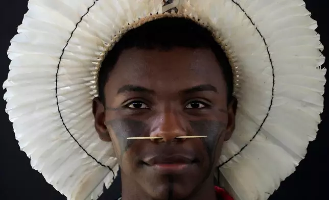 FILE - An Indigenous man wearing traditional face paint, feather headdress and piercing poses for a portrait during the opening of the "Acampamento Terra Livre," or Free Land Encampment, Brazil's largest annual Indigenous mobilization that focuses on land rights and environmental protection, in Brasilia, Brazil, Monday, April 6, 2026. (AP Photo/Eraldo Peres, File)