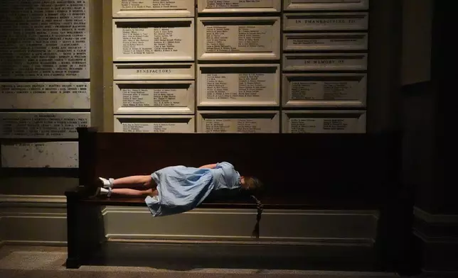 FILE - A young worshipper rests on a bench outside the nave of the cathedral during an Easter vigil at St. James Cathedral, Saturday, April 4, 2026, in Seattle. (AP Photo/Lindsey Wasson, File)
