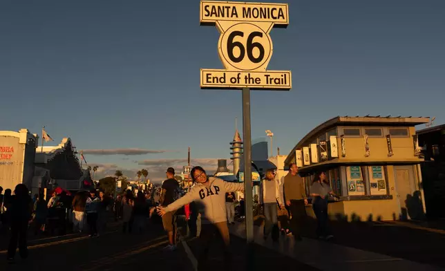 FILE - A visitor poses for photos with the "End of the Trail" Route 66 sign on the Santa Monica Pier in Santa Monica, Calif., Saturday, Nov. 22, 2025. (AP Photo/Jae C. Hong, File)