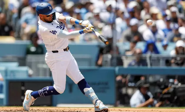 Los Angeles Dodgers' Miguel Rojas hits a two-run double, scoring teammates Kyle Tucker and Teoscar Hernandez, during the first inning of a baseball game against the Chicago Cubs, Sunday, April 26, 2026, in Los Angeles. (AP Photo/Caroline Brehman)