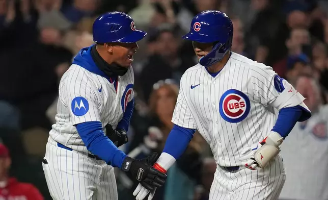 Chicago Cubs' Seiya Suzuki, right, celebrates with third base coach Quintin Berry after hitting a two-run home run during the fifth inning of a baseball game against the Philadelphia Phillies, Wednesday, April 22, 2026, in Chicago. (AP Photo/Erin Hooley)