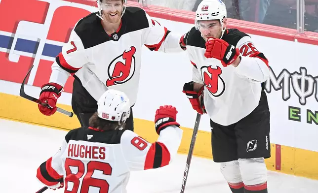 New Jersey Devils' Timo Meier (28) celebrates with teammates Dougie Hamilton (7) and Jack Hughes (86) after scoring against the Montreal Canadiens during the first period of an NHL hockey game in Montreal, Sunday, April 5, 2026. (Graham Hughes/The Canadian Press via AP)