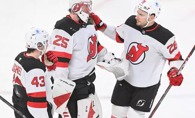 New Jersey Devils goaltender Jacob Markstrom (25), Timo Meier (28) and Luke Hughes (43) celebrate their win over the Montreal Canadiens in an NHL hockey game in Montreal, Sunday, April 5, 2026. (Graham Hughes/The Canadian Press via AP)